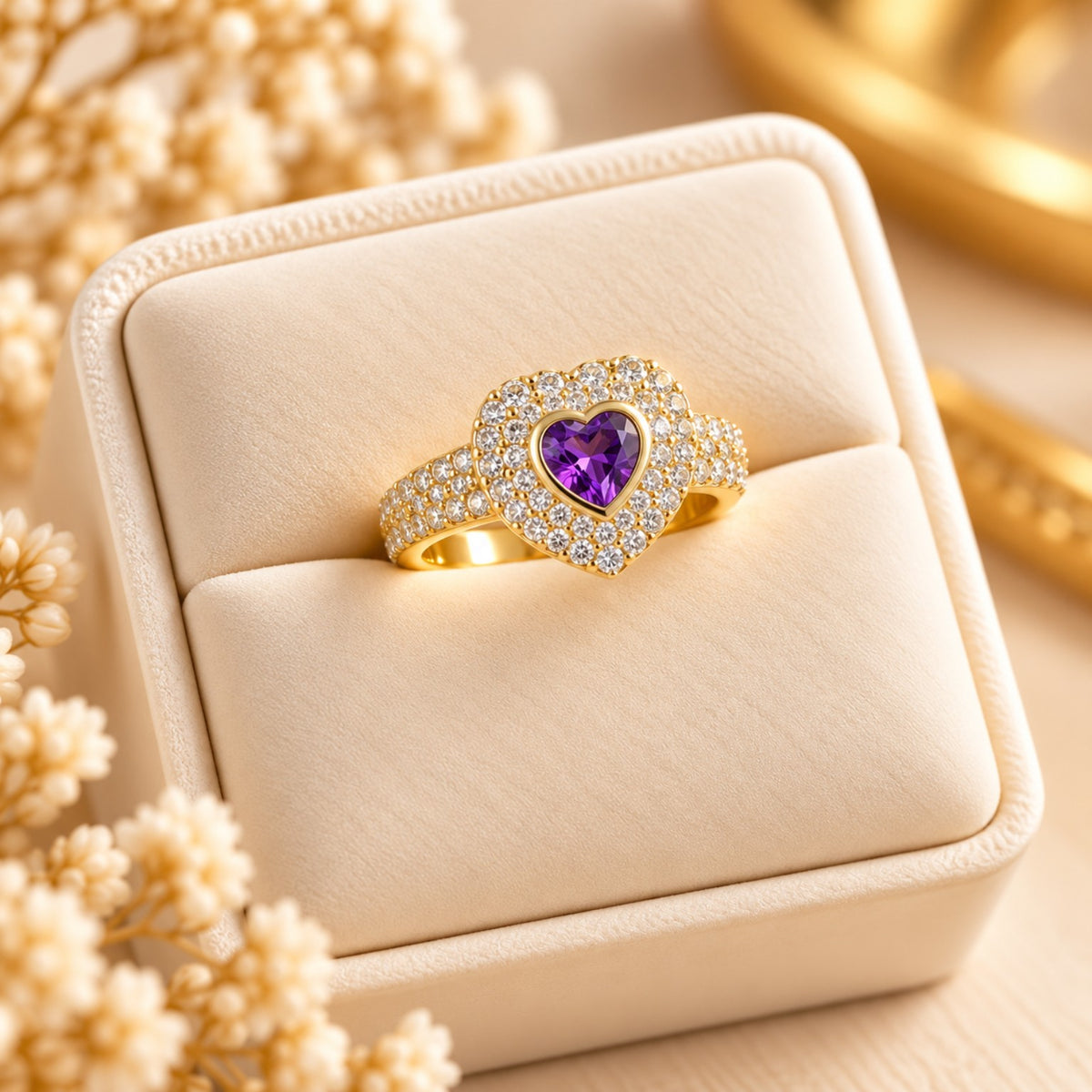 Sortija dorada con piedra violeta en forma de corazón rodeada de piedras brillantes